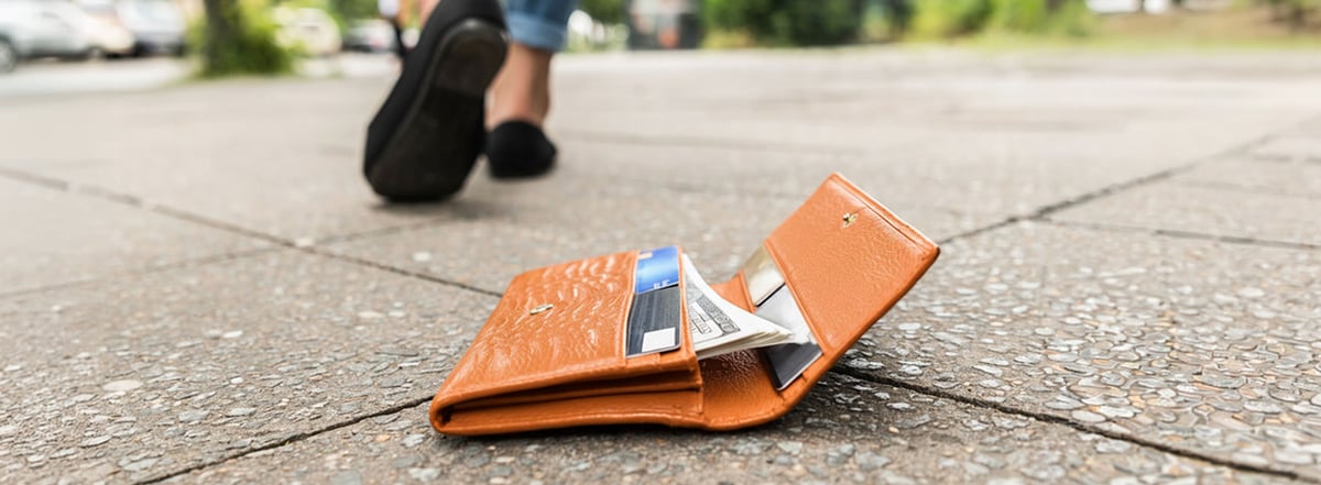 An image showing a person walking away from their dropped, lost wallet.